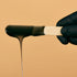 Black wax melting on a wooden applicator